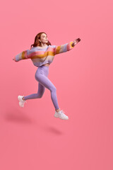Fototapeta na wymiar Portrait of happy joyous woman jumping or flying, hurry running to her dream, looking at side inspired. indoor studio shot isolated on pink studio background, copy space