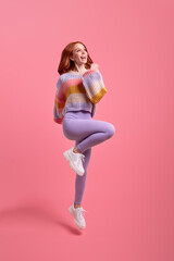 Full body of excited caucasian redhead lady jumping high raising hands first place winner wear...