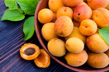 Fresh, ripe organic apricots in a bowl with leaves table
