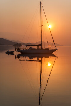 elegant sailboat and its reflection in orange light