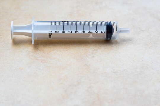 10ml medicinal syringe without needle in horizontal position on clear base with ample copy space underneath