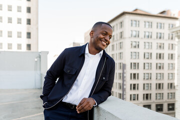 Handsome Man Smiles While Looking Over a Rooftop in the City