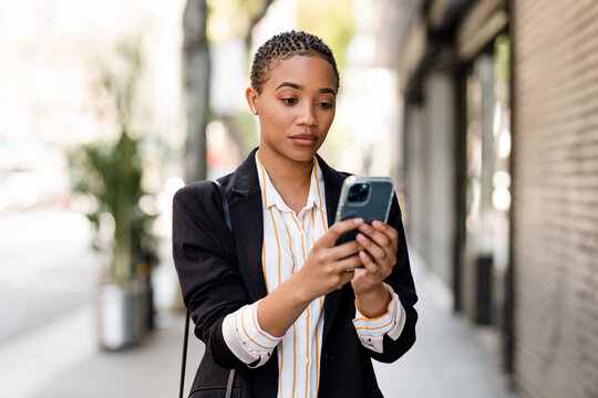 Serious Business Woman Sends a Text Message on Her Phone While Walking Through the City
