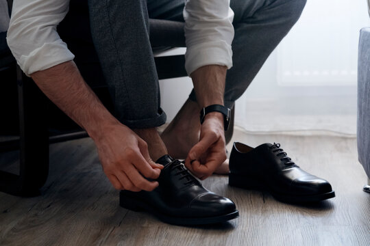 Crop unrecognizable man tying shoelaces on shoes