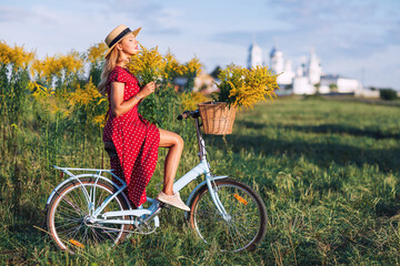 Outdoors lifestyle portrait of pretty young woman sitting on the bicycle. Inhaling the scent of...