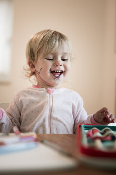 Adorable little blond girl playing with paint and colored markers