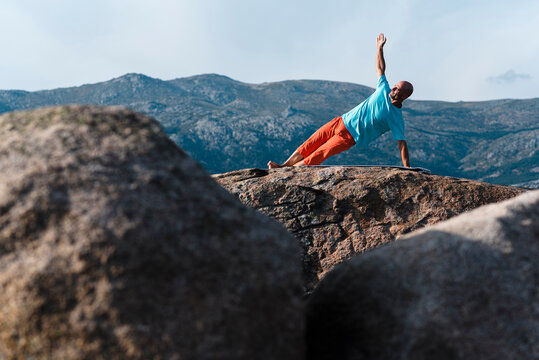 Mature man doing Side Plank in mountains 