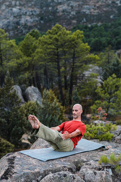 Adult man doing pilate pose in mountains 