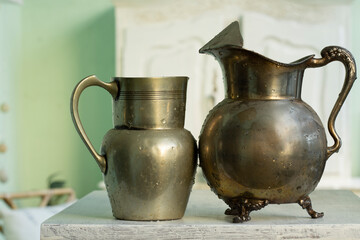 pair of antique metal vases on white wooden base and unfocused background.