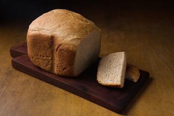 whole wheat bread on wooden board with a cut slice