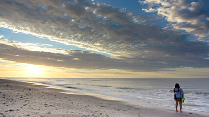 woman watching the sunrise on a lonely beach