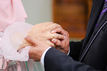 Close up a man places wedding ring on a woman