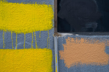 Dripping yellow and brown paint covering graffiti on building wall, close up