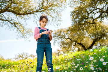 Close-up of little girl with daisies wearing an overall at field
