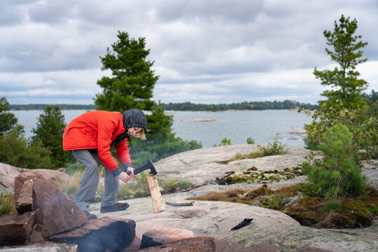 Boy Splitting Campfire Wood with Small Axe on Wilderness Camping Trip to Fox Islands Georgian Bay Killarney Ontario Canada
