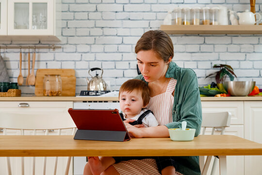 Mother and toddler son using tablet in kitchen