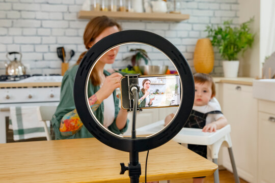 Mother feeding cute son and recording video for vlog