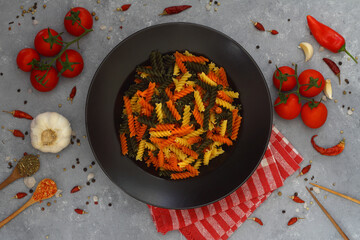 Colorful various raw fusilli on black plate