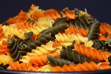 Three Colors Rotini Pasta. Pasta fusilli tricolore background. Abstract texture of colorful pasta....