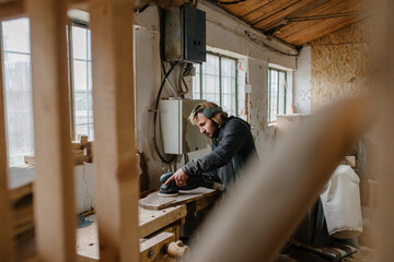 Male sanding a piece of wood in a shop