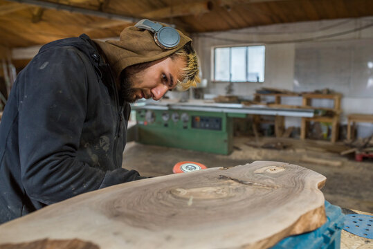 Worker sanding the live edge of a wood plank