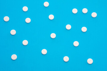 Background for pharmacy or medicine. White pills with medicine are on a blue uniform background, forming a polka dot pattern