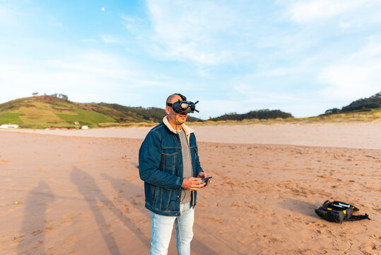 Man in VR headset controlling drone at seaside 