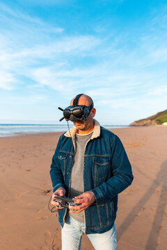 Man in VR headset controlling drone at seaside 