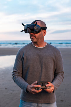 Man controlling drone in glasses of virtual reality on beach 