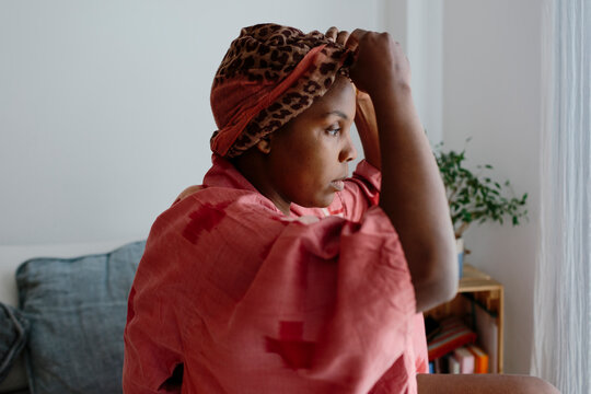 Woman adjusting head-wrap in bedroom