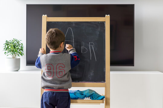 Kid doing homework on the blackboard at home