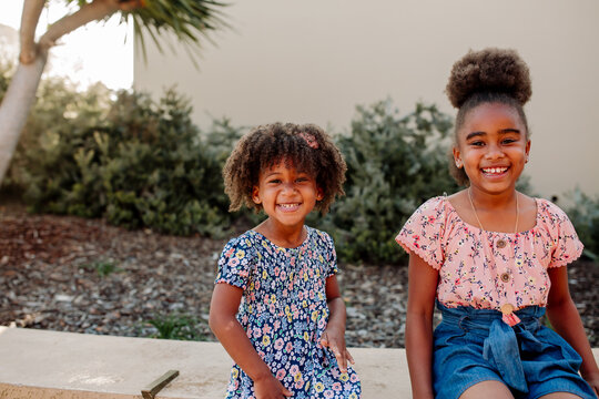 Young Black sisters sitting outside