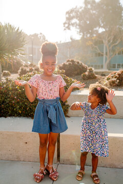 Young black girl mimics big sister