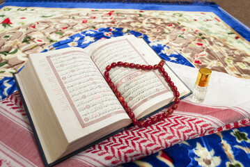 closeup of Islamic book Quran rosary and shemagh scent on colorful prayer mat,religious concept