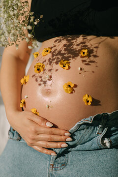 Crop of pregnant woman with flowers
