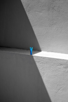A blue clothes peg playing with the lines of sunlight.