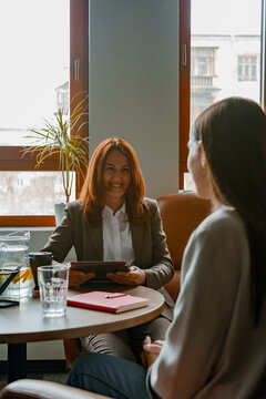 Cheerful female colleagues discussing plans in office