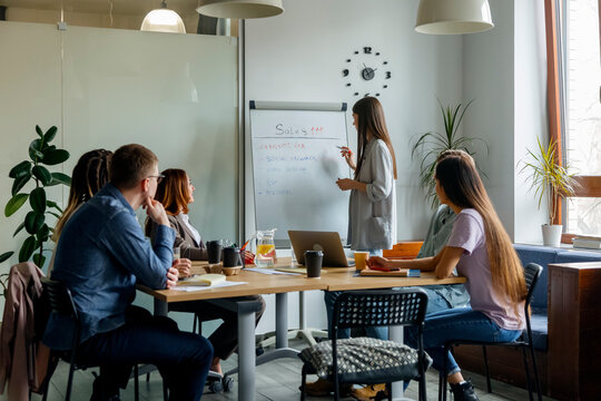 Woman explaining project strategy to company of colleagues in office