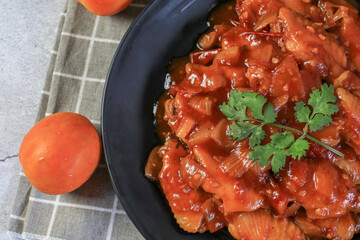 Chicken with tomato and vegetables close-up on plate. Asian food and meal.