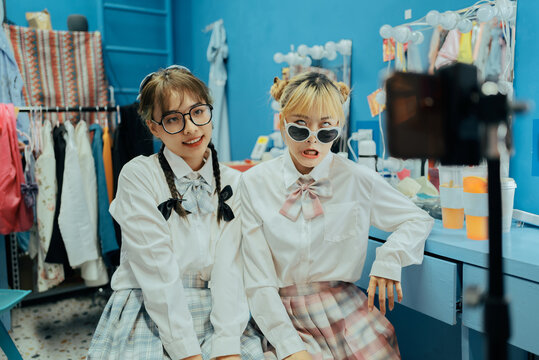 Two young Asian women take pictures and live broadcast with cell phone