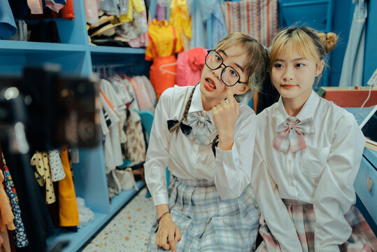 Two young Asian women take pictures and live broadcast with cell phone