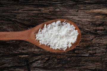 Fototapeta na wymiar Grated dry coconut in wooden spoon on rustic wooden background.