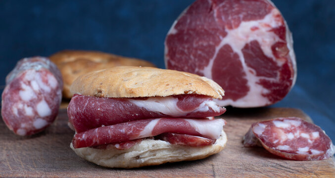  S&aacute;ndwich de bondiola de carne de res. Concepto de alimentaci&oacute;n tradicional realizada en casa. Chorizos o salchichas caseras en tabla de madera. 
