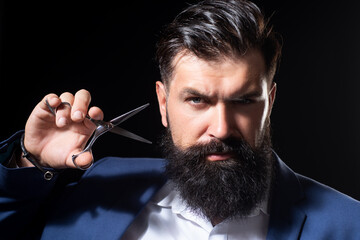 Closeup bearded man, portrait of man with long beard and moustache. Barber scissors for barber shop. Vintage barbershop, shaving. Brutal serious male with modern hairstyle on black.