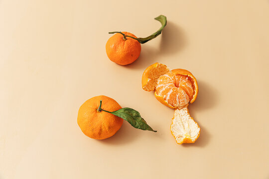 Peeled leafy oranges on orange background