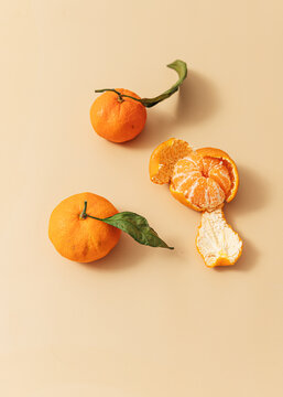 Peeled leafy oranges on orange background