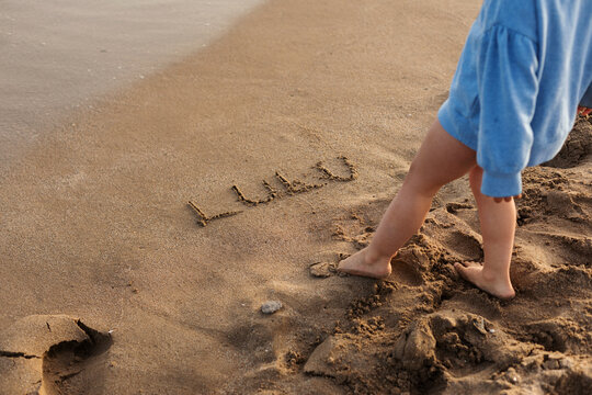 child and her name in the sand