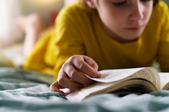 Close Up of Little Girl Flipping Page as she Reads a Chapter Book on her Bed