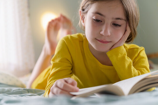 Little Girl Reading a Chapter Book on her Bed