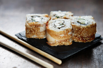 sushi rolls with chopsticks on dark background